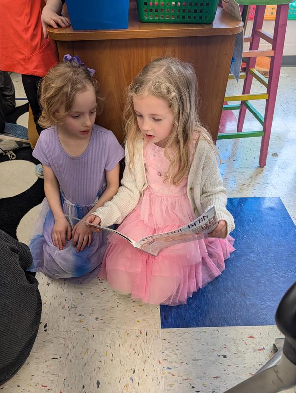 two girls in dresses reading together