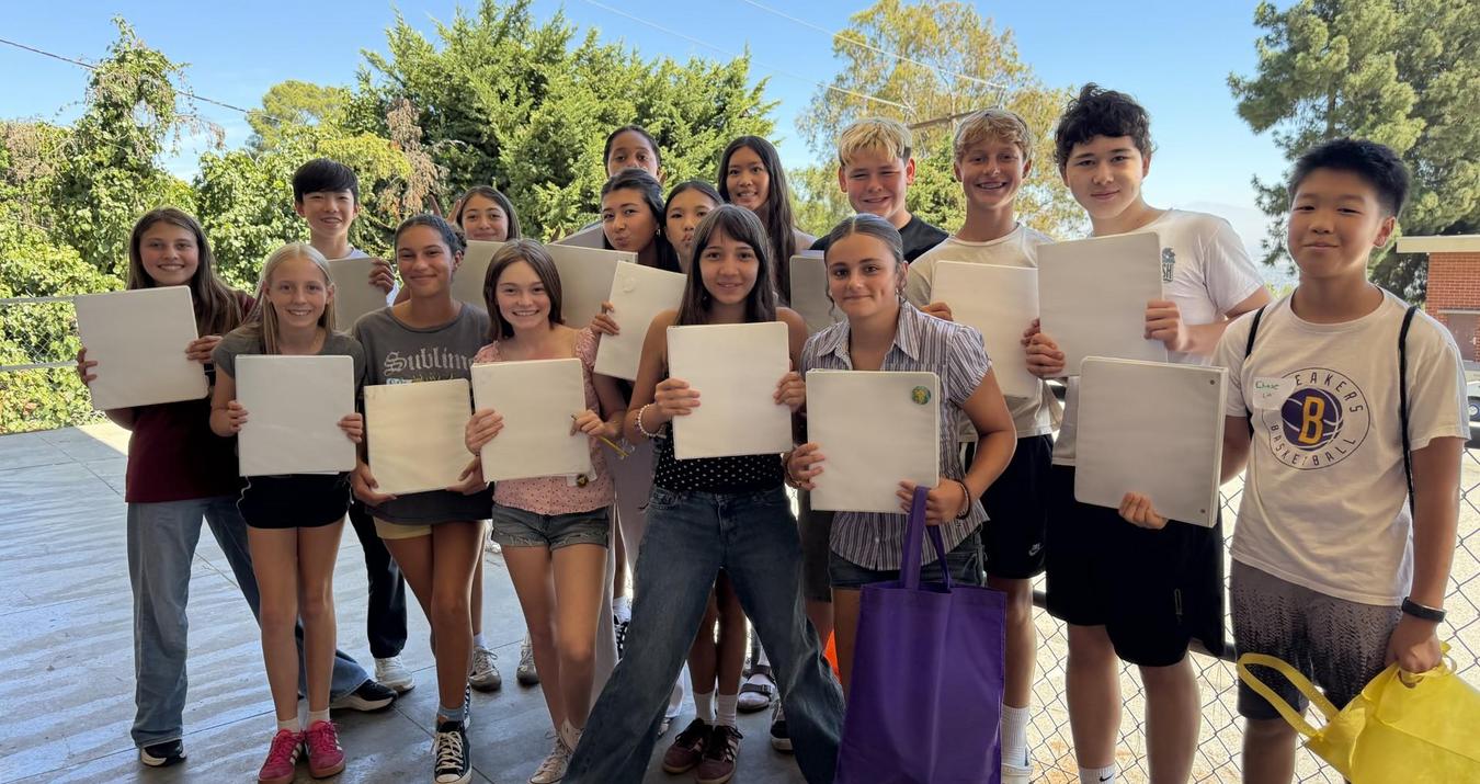 Large group of students holding blank papers outdoors.