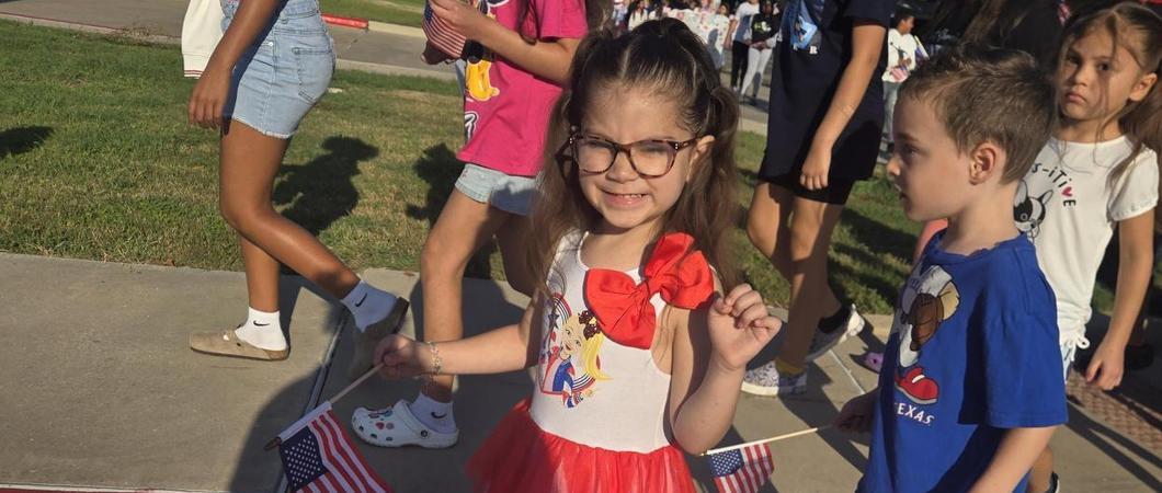 A child dressed in Red White & Blue outfit smiling.
