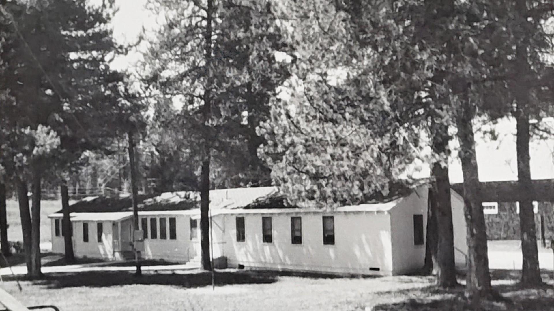 Black and white view of modular school buildings in a forested area.