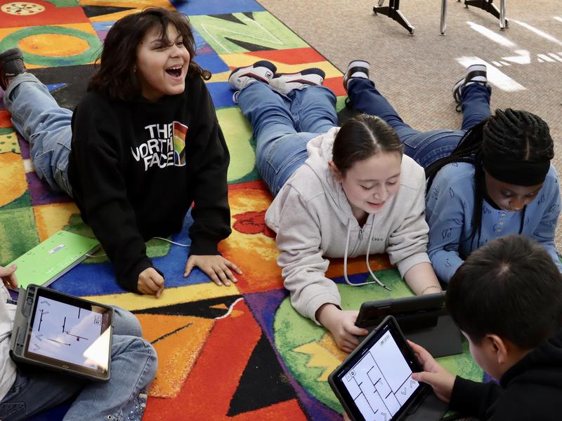 Students working on ipads on a carpet
