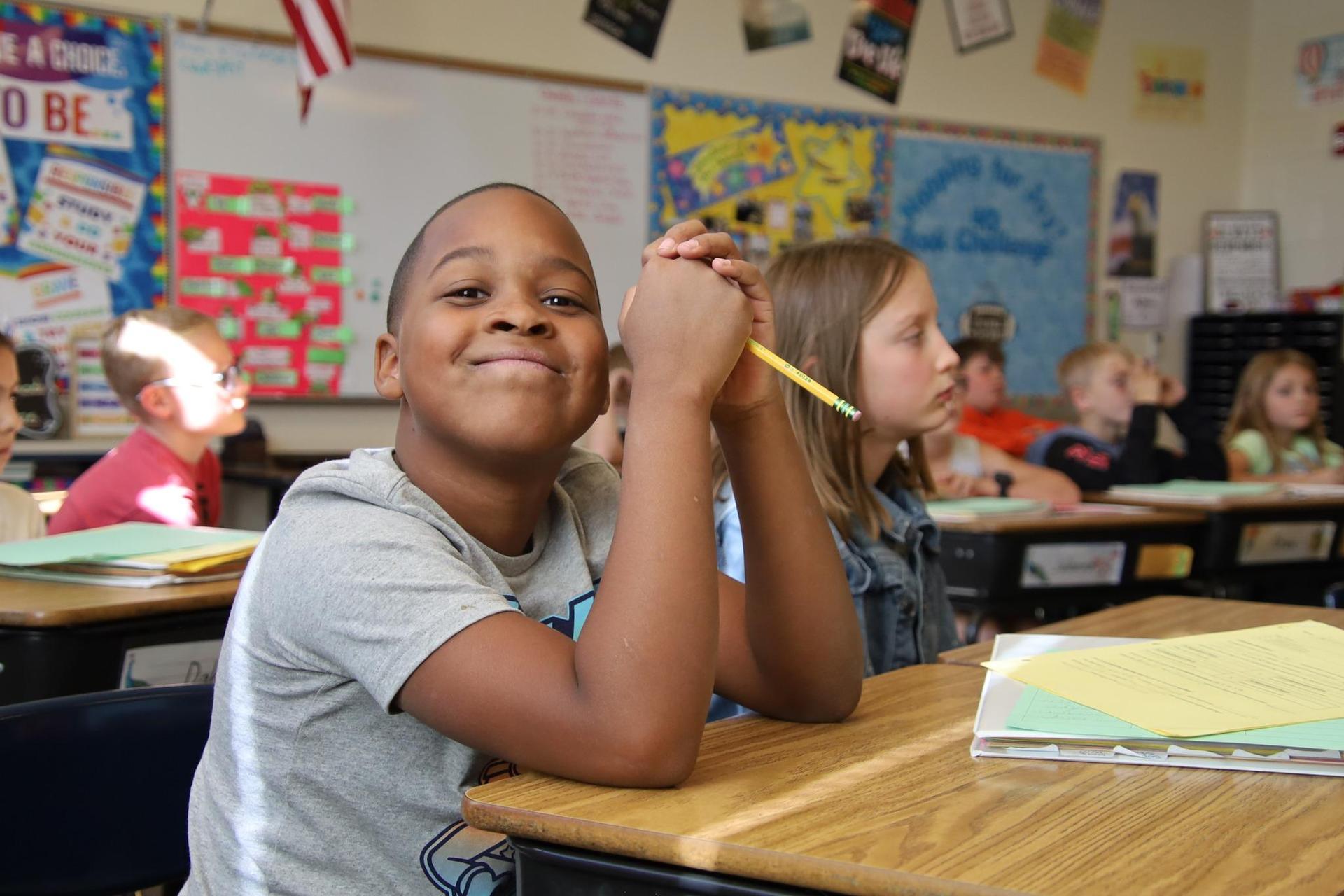 elementary student smiling at the camera in a classroom