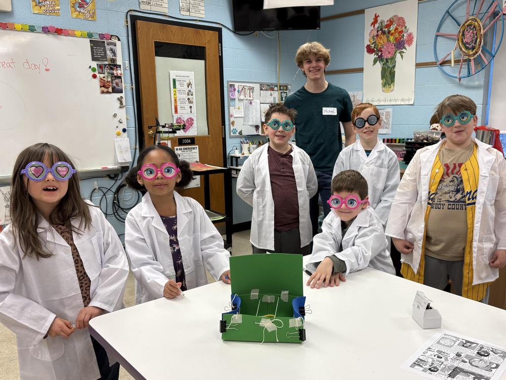 Elementary students wearing science lab coats and silly glasses participating in an after school STEM club.