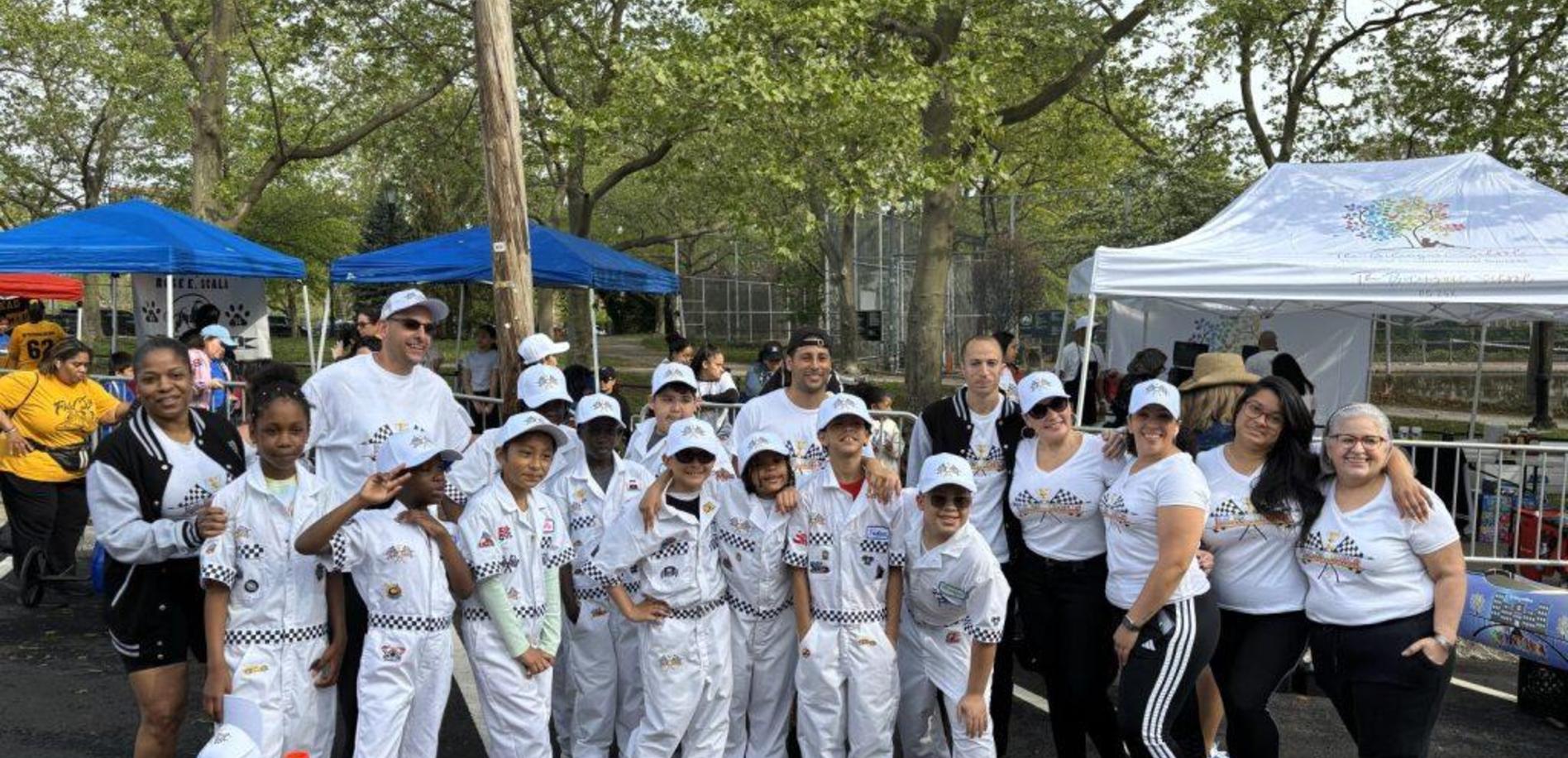 A diverse group of children and adults in matching outfits at an outdoor event.