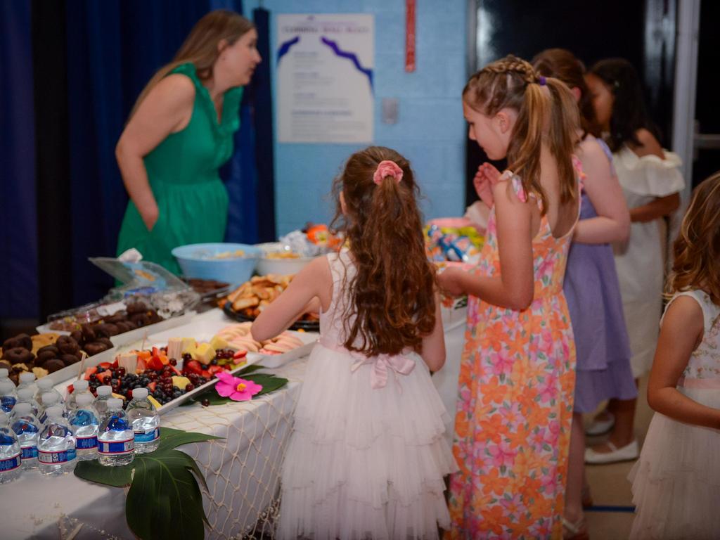 Girls at a food table with platters of cookies and fruit at a dance.