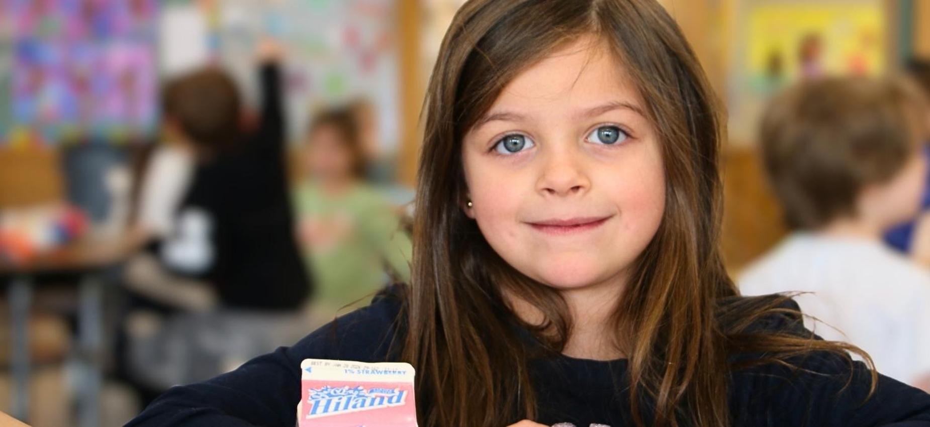 Girl posing with a card in a classroom setting.