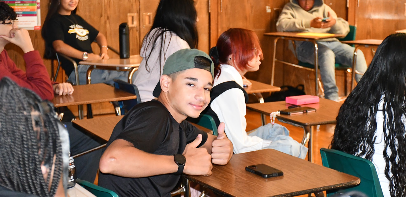 Student in class on first day of school giving the thumbs up.