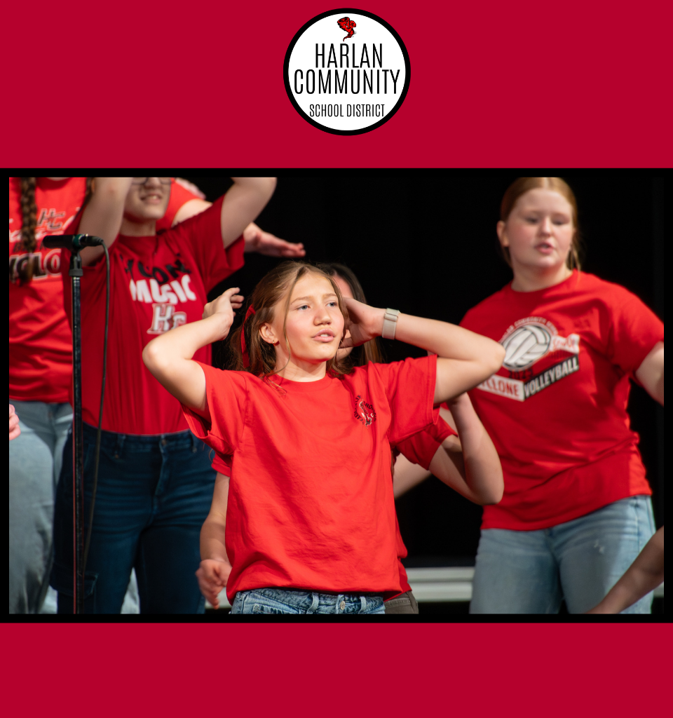 A girl in a red shirt performing on stage with others.