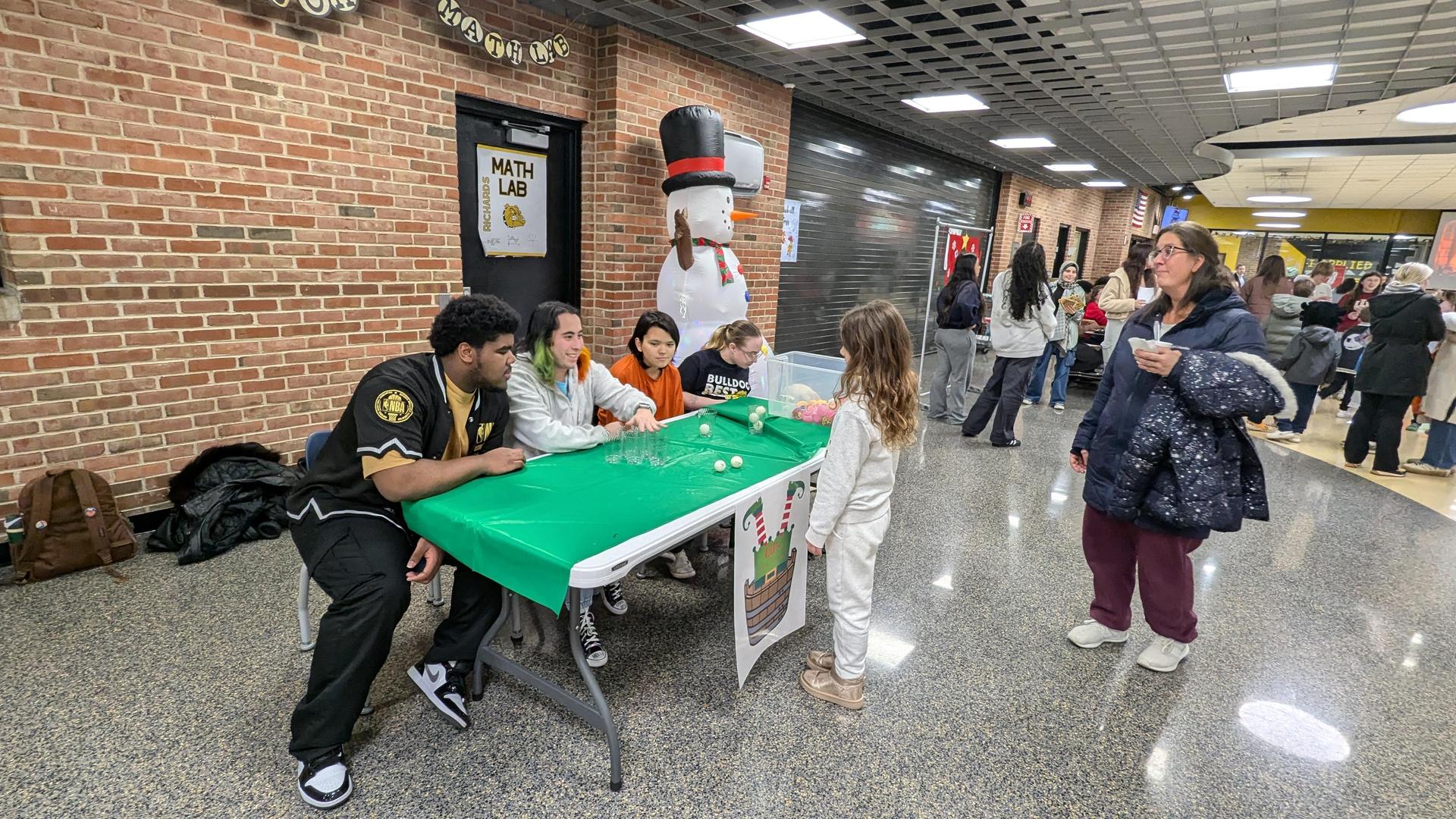 A group of teenagers interacting with a young child at a table