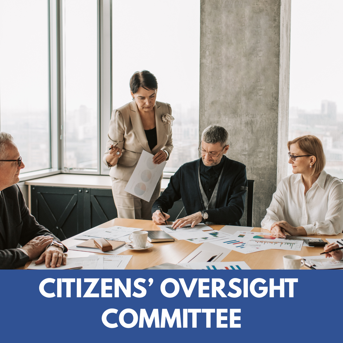 photo of men and women working around a table with lots of papers on the table