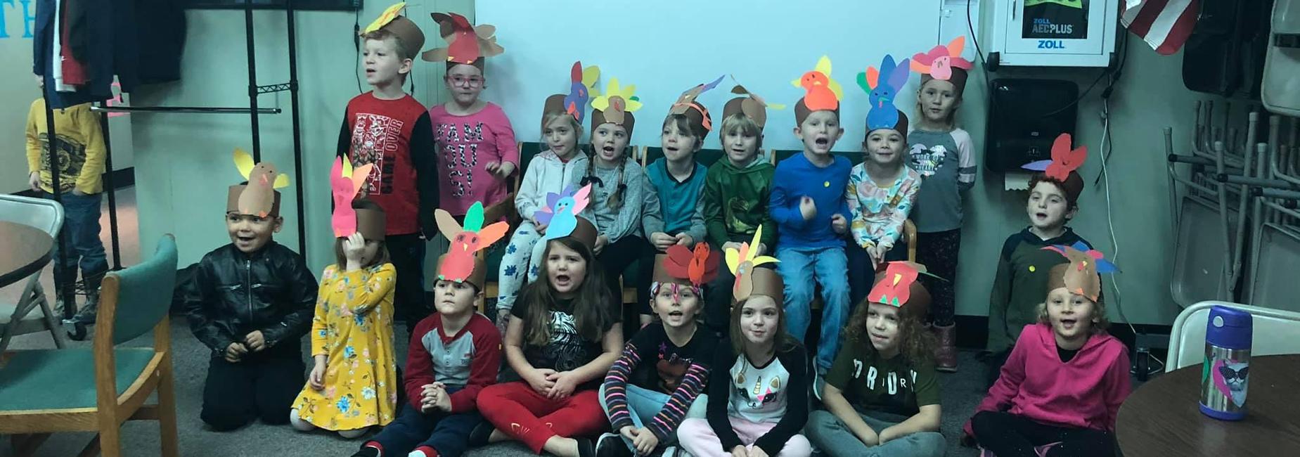 students wearing hats shaped like thanksgiving turkeys