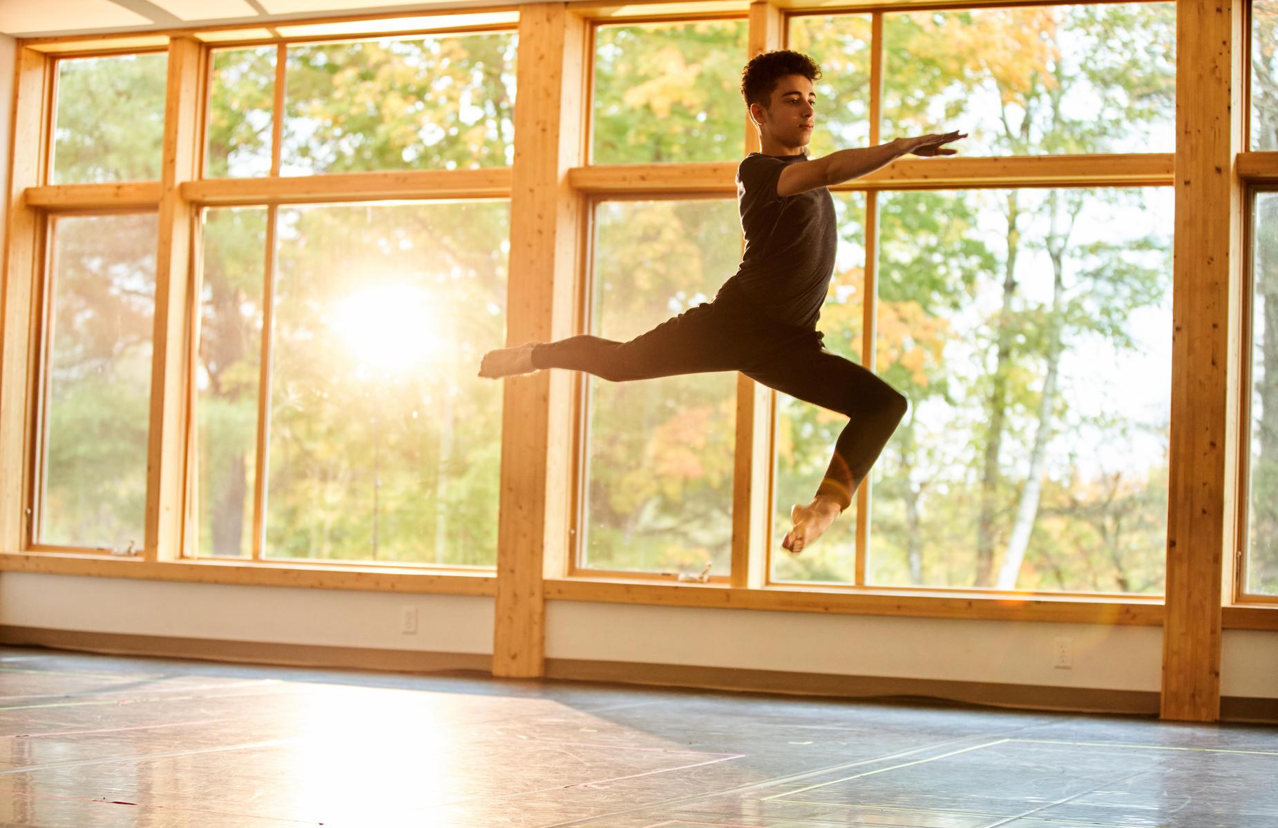 A student leaping in the dance studio.