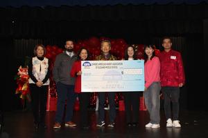 Group of people presenting a large check at a celebration event.