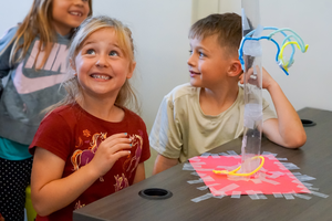 Two students working in STEM Mobile Lab, using craft item to build a tall structure..