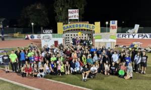 Large assembly of students grouped around a themed structure at night for school spirit.