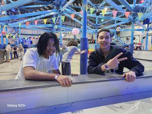 Two friends smile and pose by a railing in a vibrant activity center.
