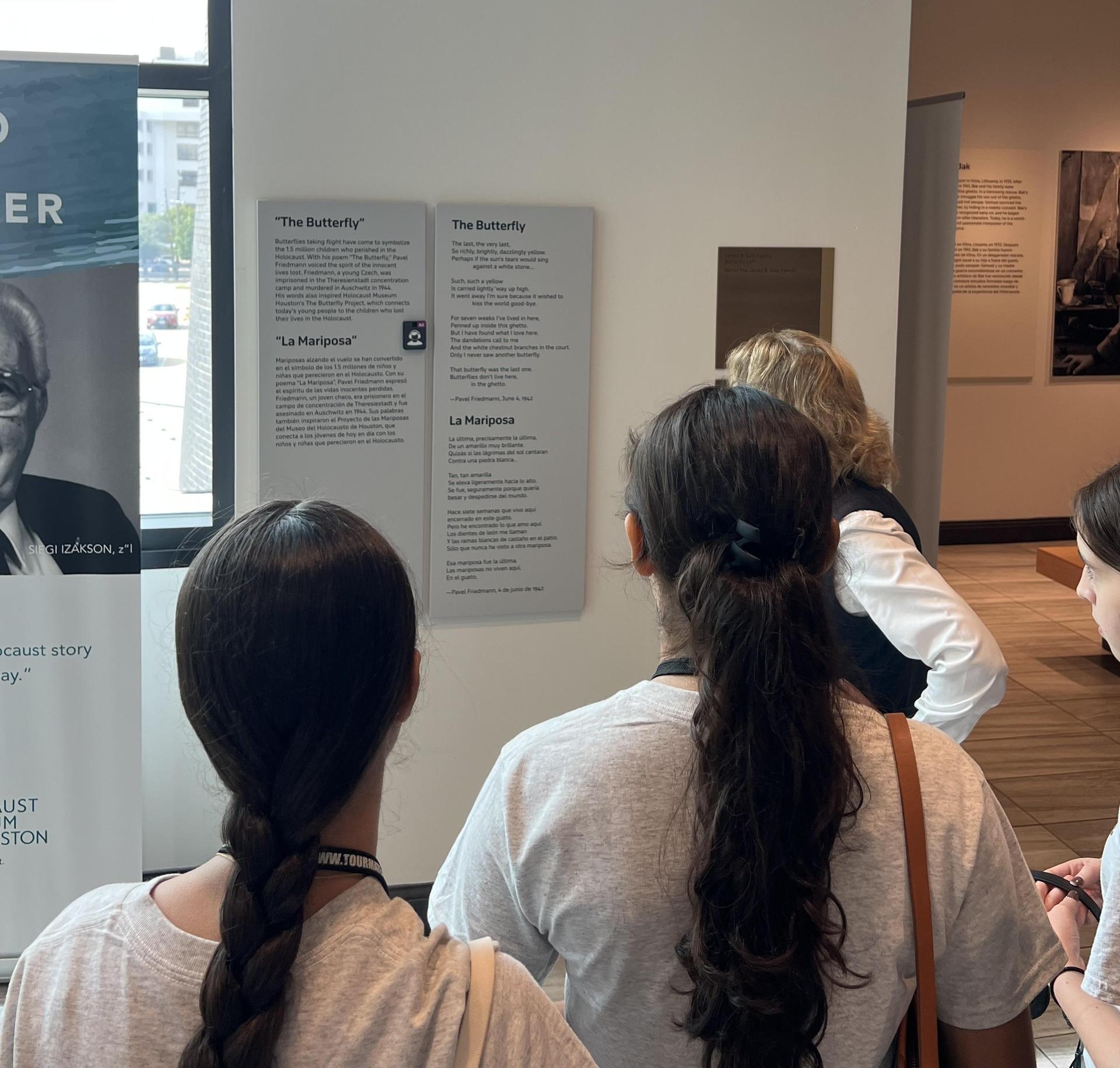 a lady speaking to a group of people at the Holocaust Museum