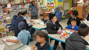 The boys listen to Morah Dena teaching.