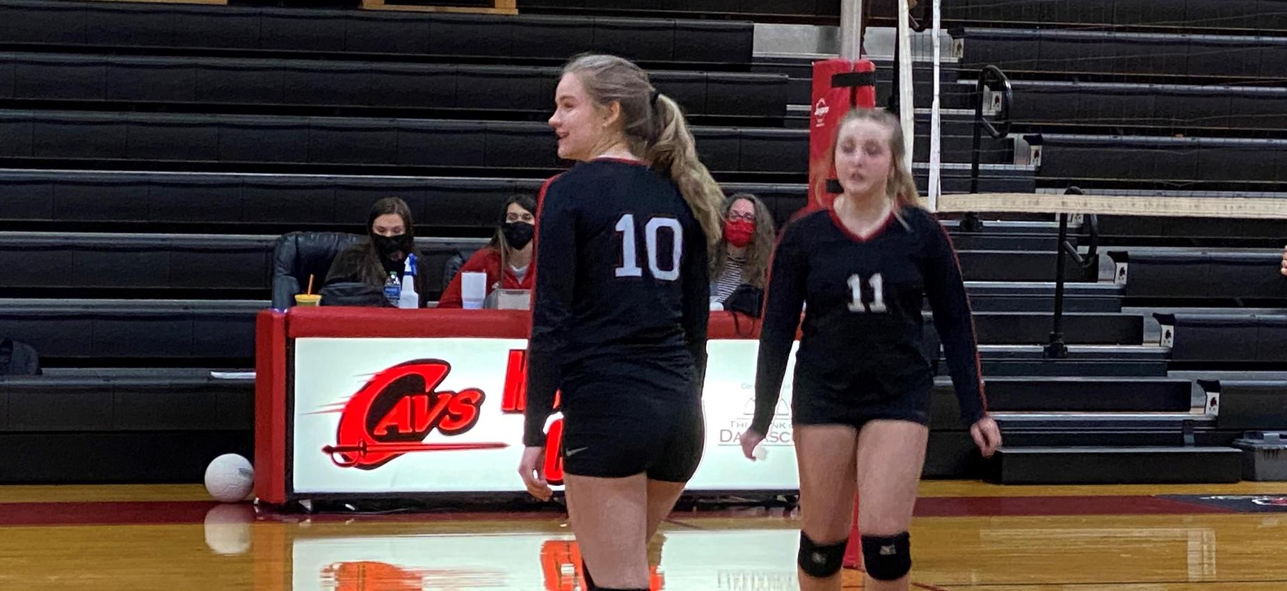 Two volleyball players play in a gym.