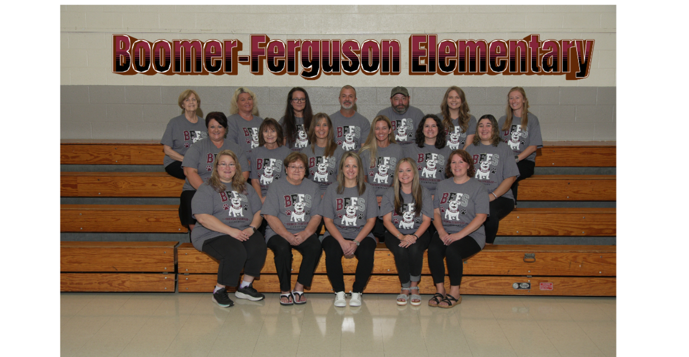 Group of adults in matching shirts posing in a school gymnasium.