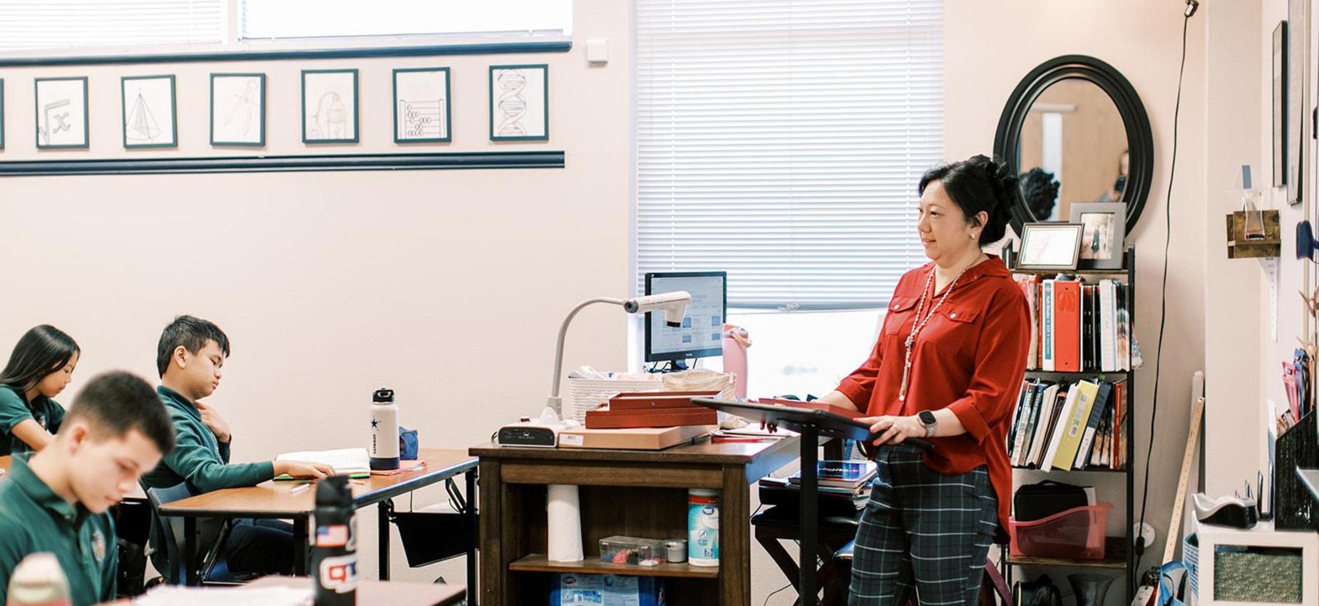 Teacher leads a lesson at the front of a middle school classroom