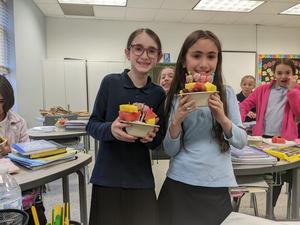 two girls display their edible fruit arrangement.