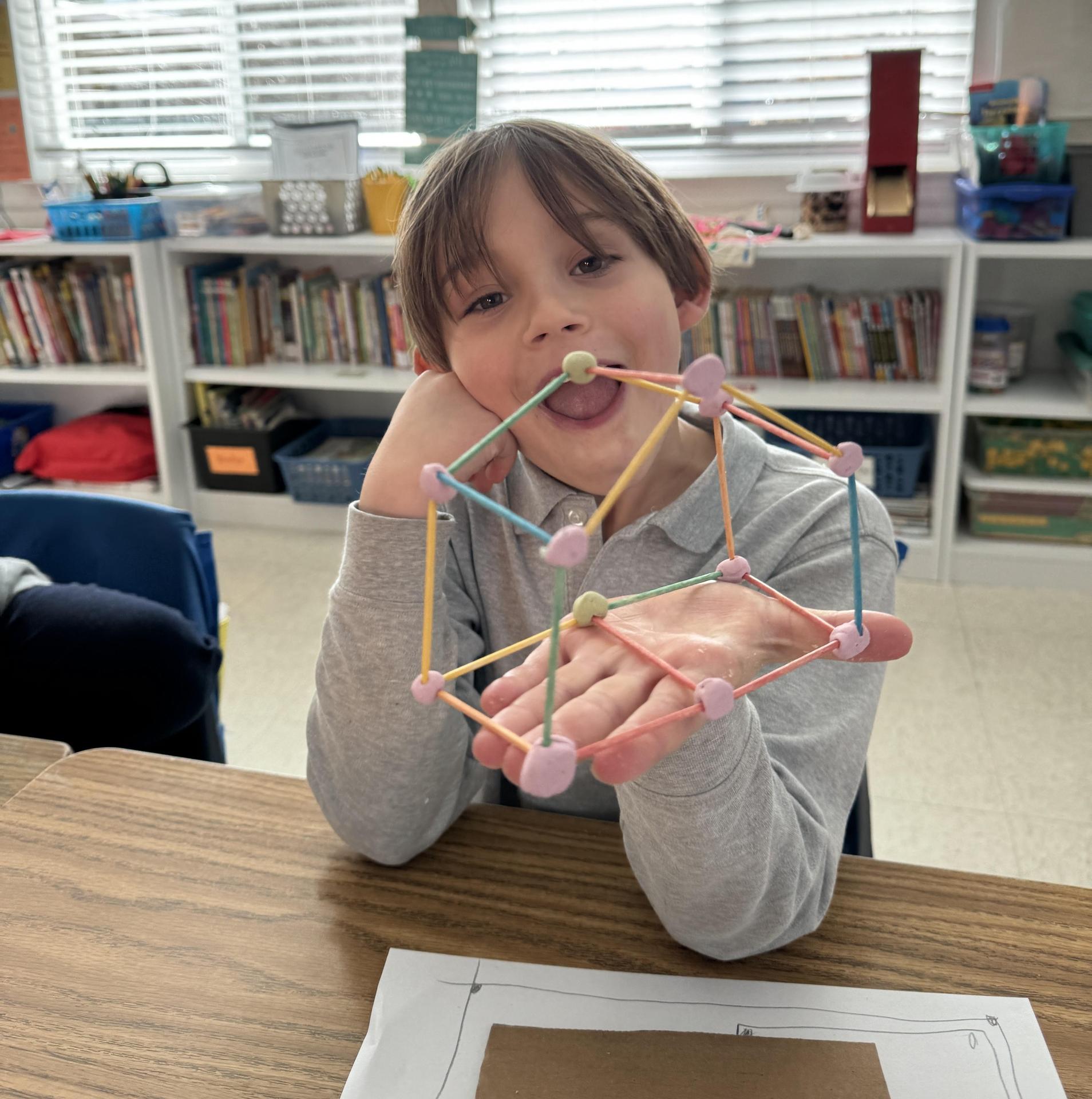 Student holds 3D structure made out of toothpicks.