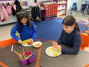 second grade girls making fruit salad.