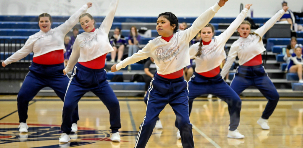 Dancers execute a synchronized routine on a gym floor.