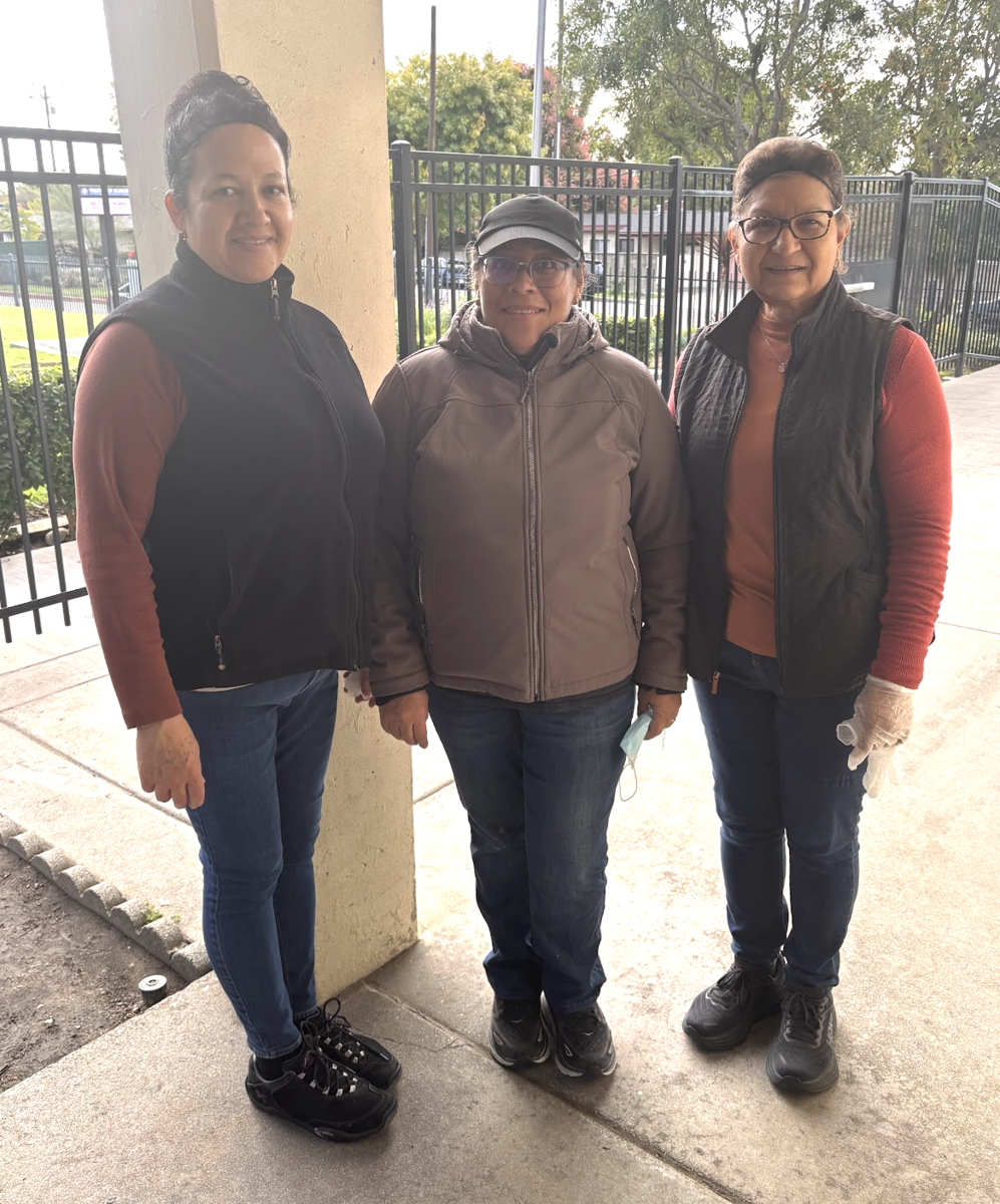 Three women standing in the cafetria, smiling with welcome signs above them.
