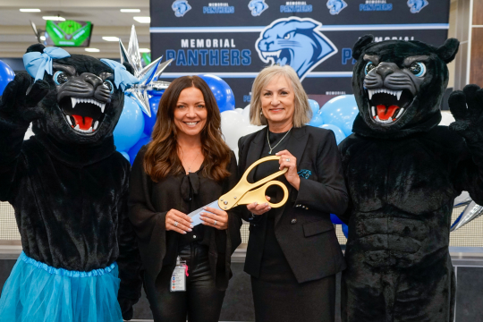 Principal Campbell and Dr. McCord pose with the two mascots while holding the big scissors for the ribbon cutting.