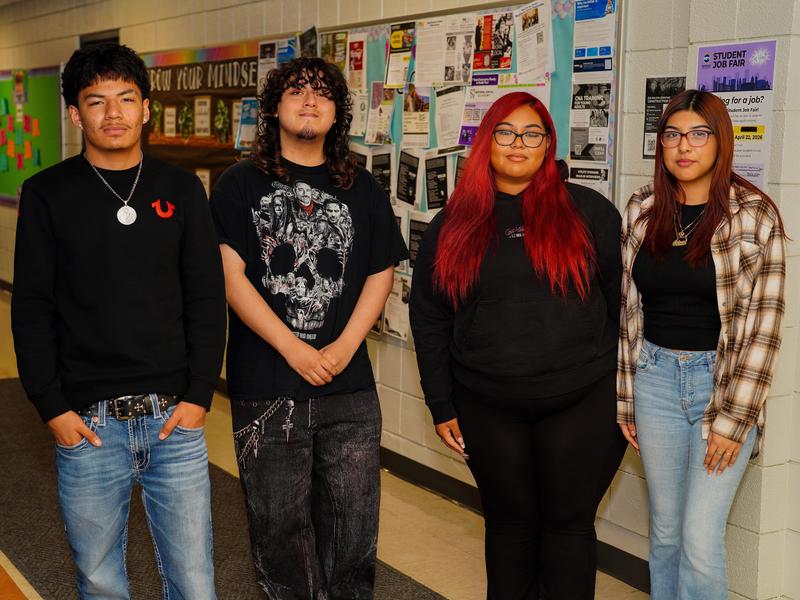 Four students posing together for a photo inside the school.
