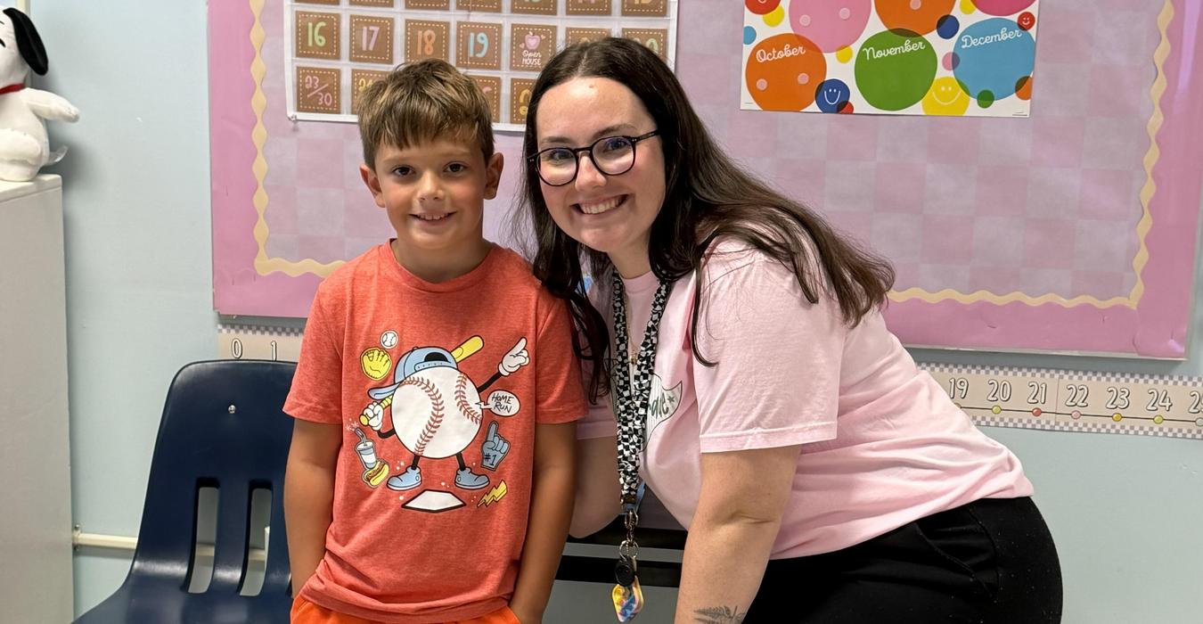 Child and adult smiling together in a classroom setting.