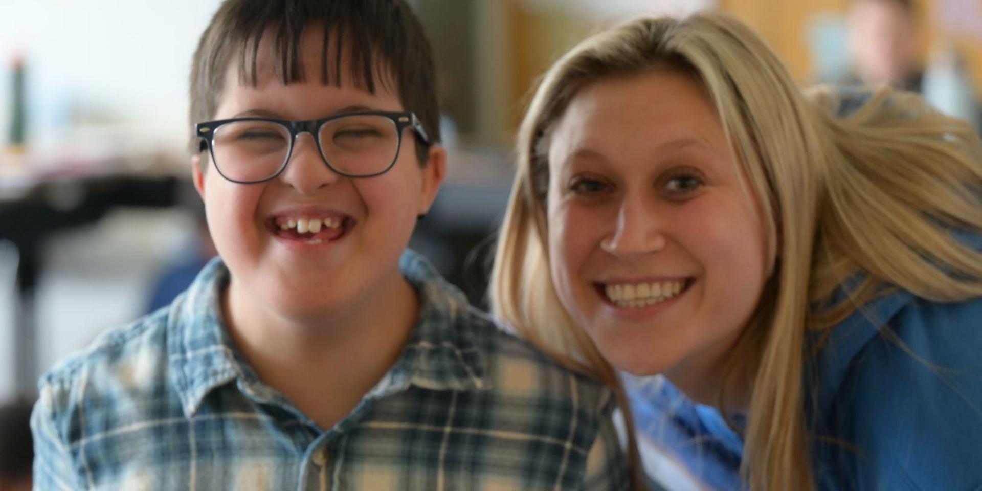 Smiling boy with glasses and a woman posing together.