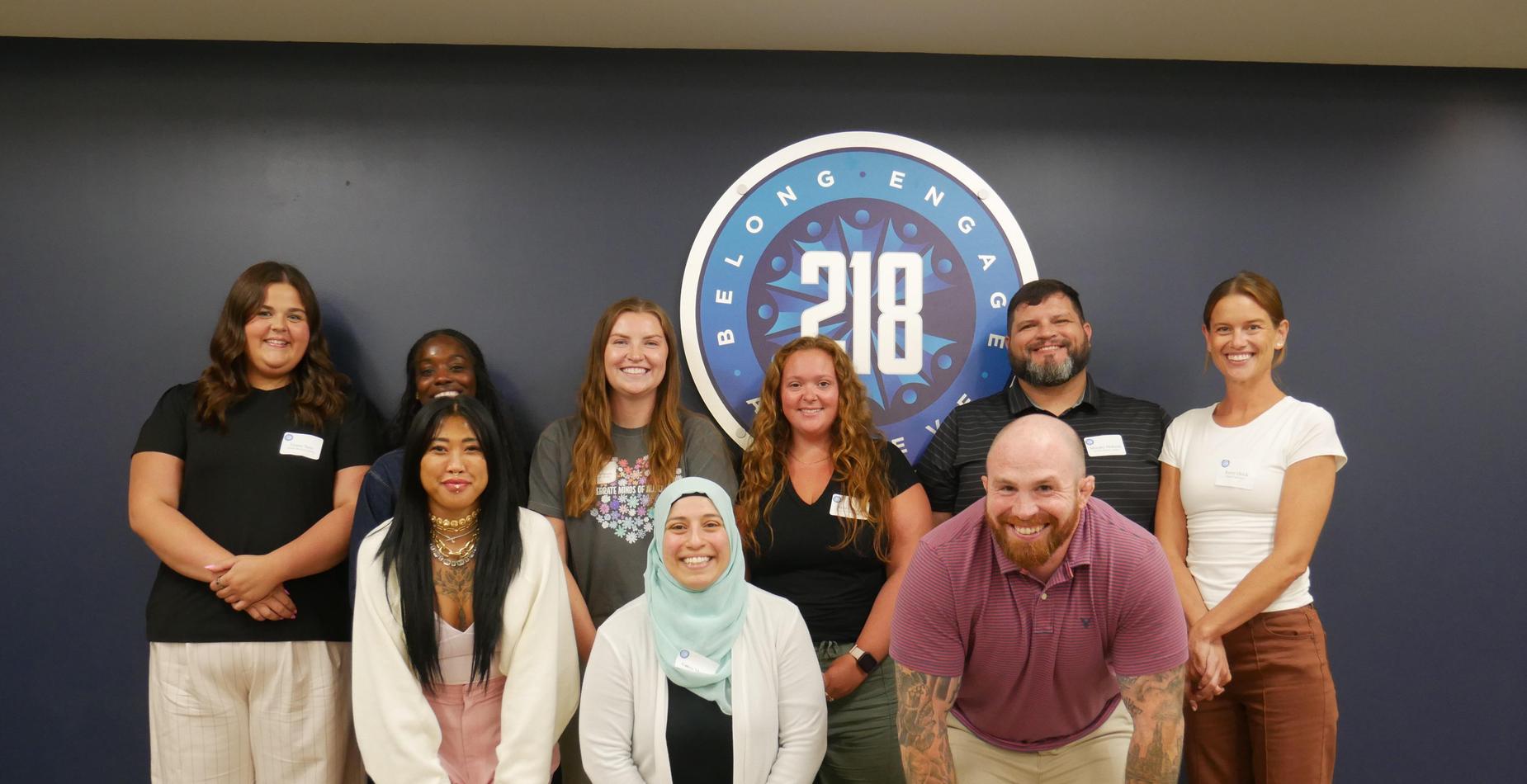 Group of individuals posing together in front of a 218 logo on a wall.