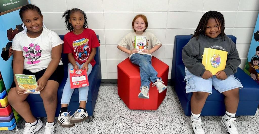 Students smile holding books.