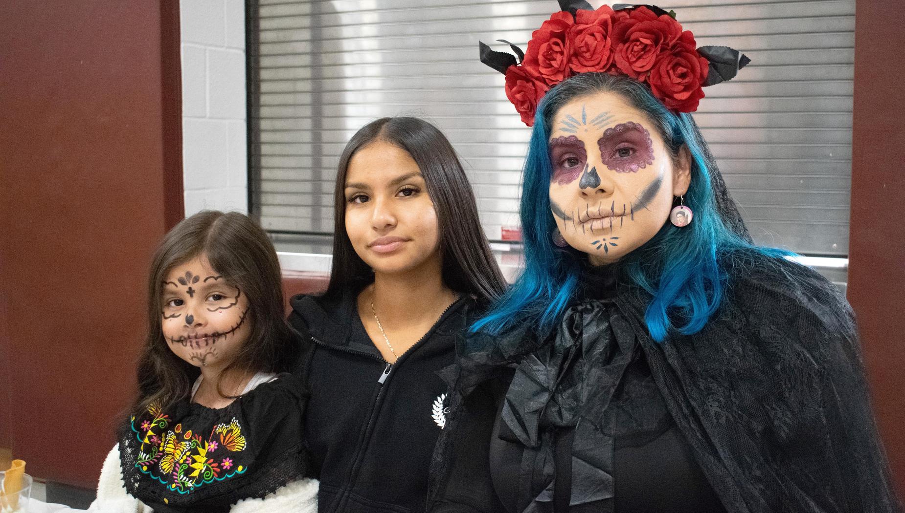 Three women in festive attire with colorful face paint and flower crowns.