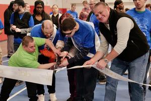 Three gentlemen cutting ribbon for Walk Fundraiser; people in the back getting ready to walk