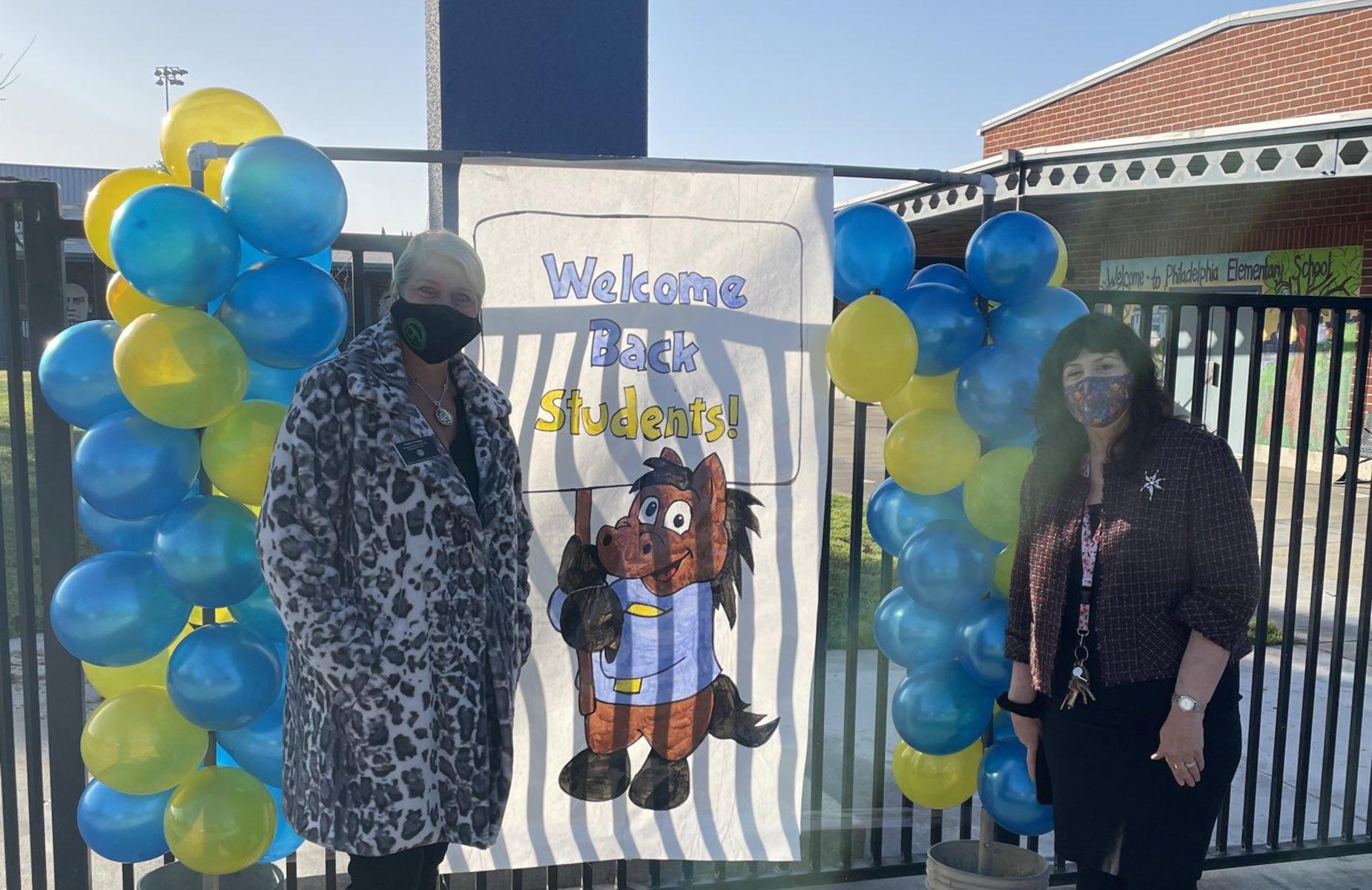 School administrators welcome students in front of school