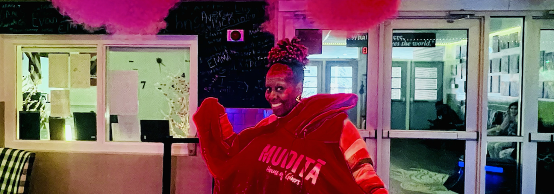 Person wearing a large red garment, posing in a colorful venue.
