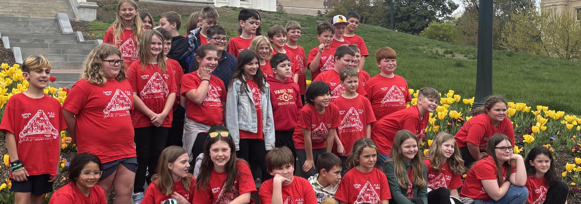 Students on a field trip pose for group photo all dressed in MES matching shirts