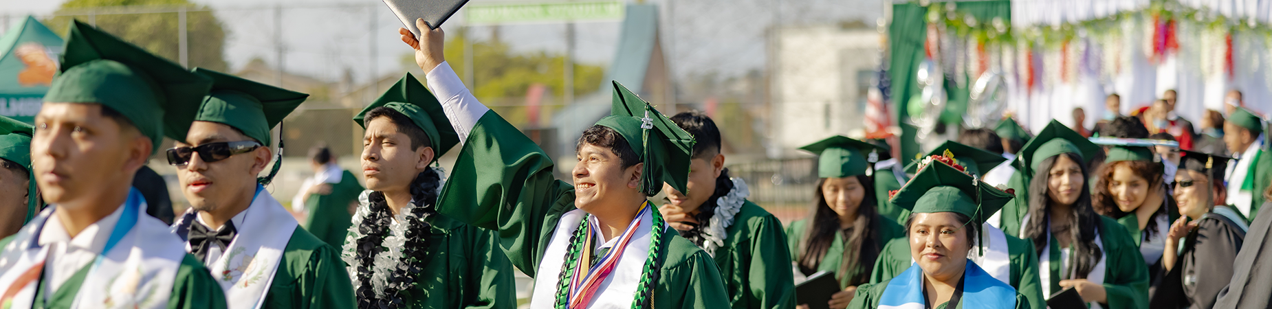 high school graduates in green caps and gowns