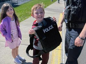 A smiling student tries on a police protective vest.