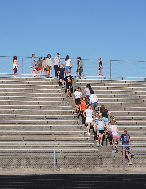 Groups of students climb up and down the stairs in the stadium.
