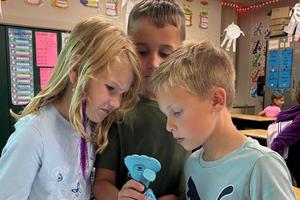 Zoe Miller, Waylon Jack, and Liam Driskill observe an image through the new microscope