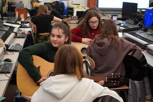 a line of girls playing guitars in pairs