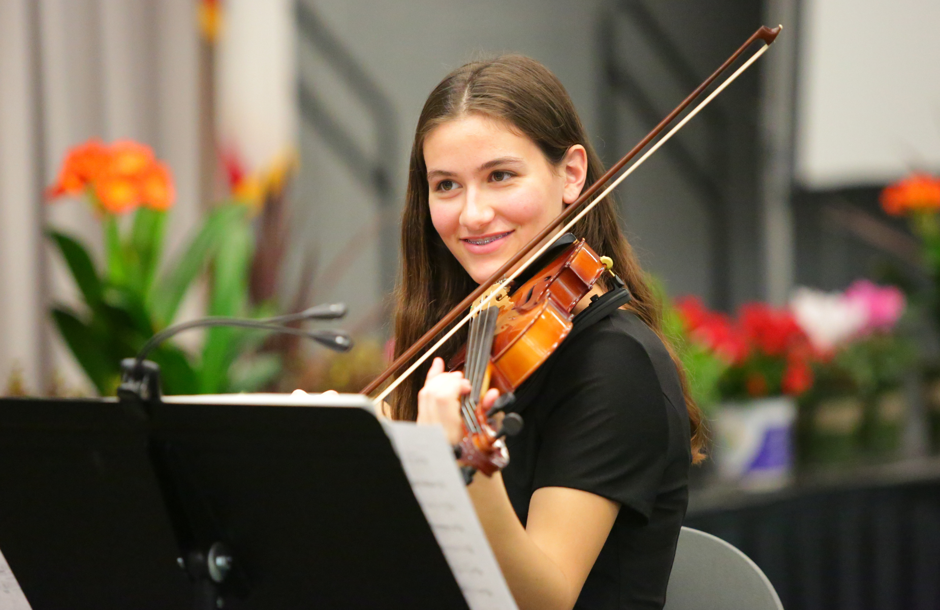 Shuffle banner for district homepage - infographic of a student playing the violin at a celebration for all district students.