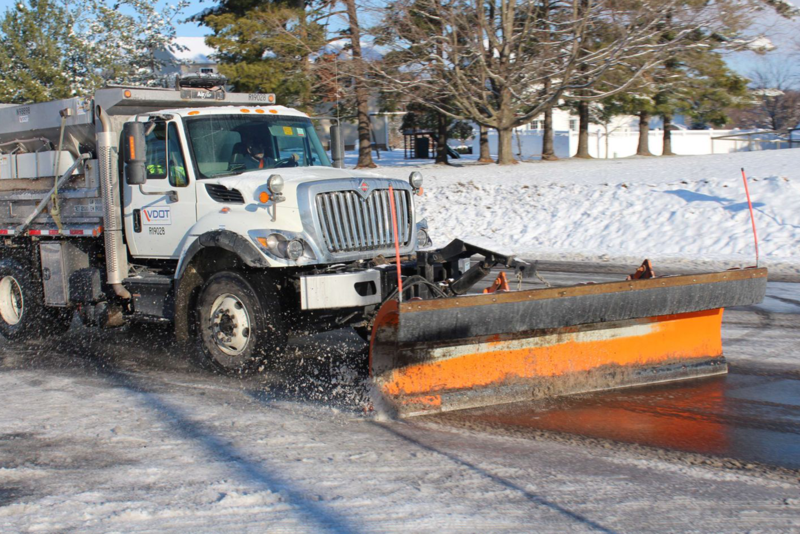 A VDOT snow plow clears snow from a roadway.