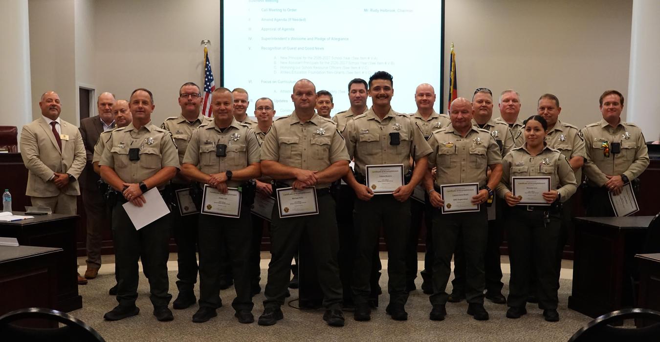Group of law enforcement officers holding certificates in a formal setting.