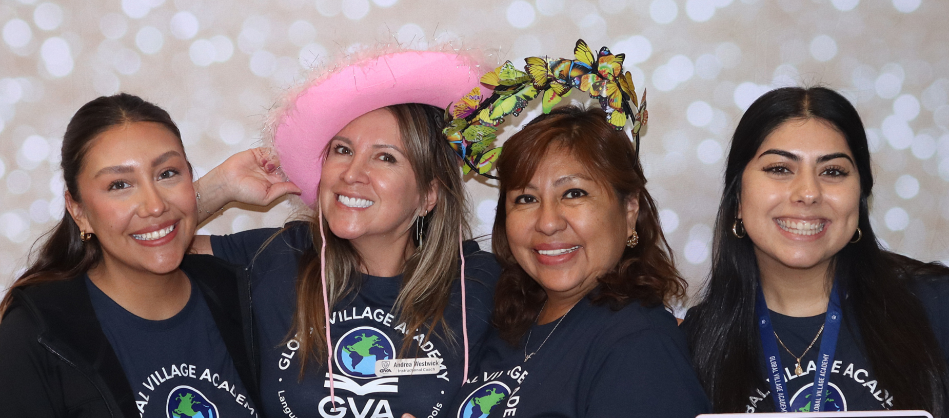 Four women smiling together in a festive setting with colorful hats.